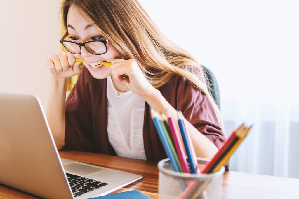 Woman biting pencil and looking stressed as she can not remember her password